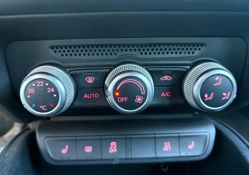 Gros plan sur la commande de climatisation automatique et les boutons des sièges chauffants d'une Audi A1 Sportback grise.