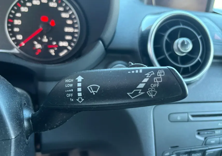 Gros plan sur la commande des essuie-glaces côté gauche du tableau de bord d'une Audi A1 Sportback grise avec toit noir.