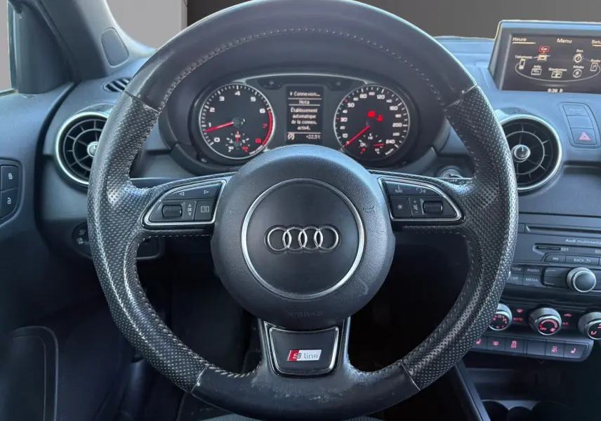 Vue centrée sur le volant sport S-Line noir avec tableau de bord et écran multimédia de l'Audi A1 Sportback 2014.