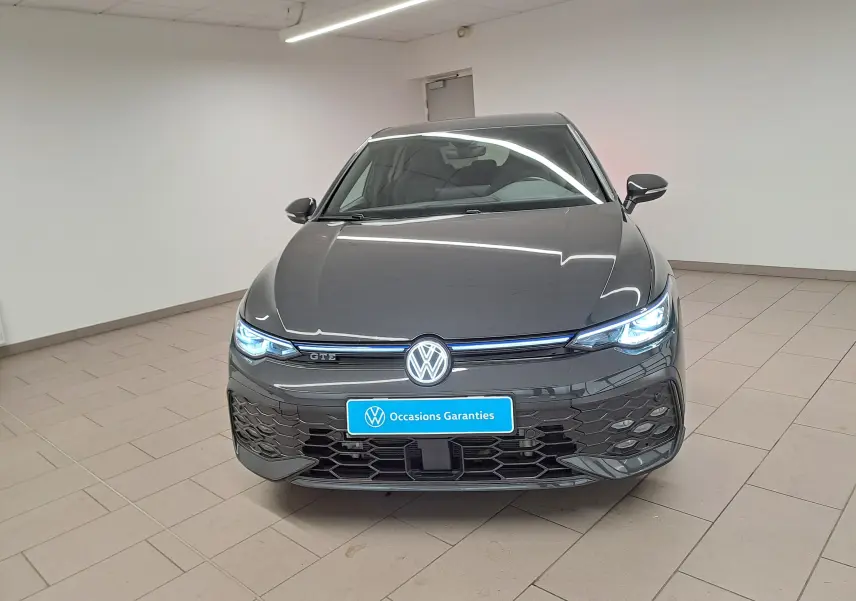 Volkswagen Golf 1.5 eHybrid 272 DSG6 GTE gris Urano vue 3/4 avant avec phares allumés et jantes sport.