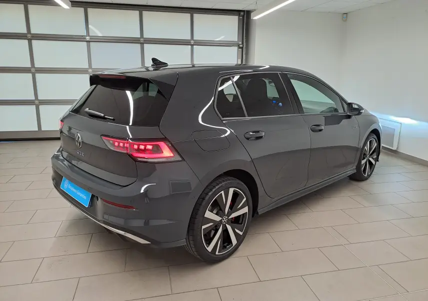 Volkswagen Golf 1.5 eHybrid 2025 gris Urano vue 3/4 arrière droit avec feux LED et jantes distinctives GTE.