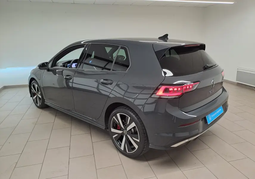 Volkswagen Golf 1.5 eHybrid 2025 en gris Urano, vue 3/4 arrière droit avec feux LED et jantes sport noires.