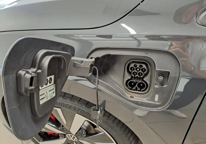 Prise de recharge ouverte côté gauche d’une Volkswagen Golf 1.5 eHybrid 272 DSG6 GTE gris Urano, roue et jante visibles.