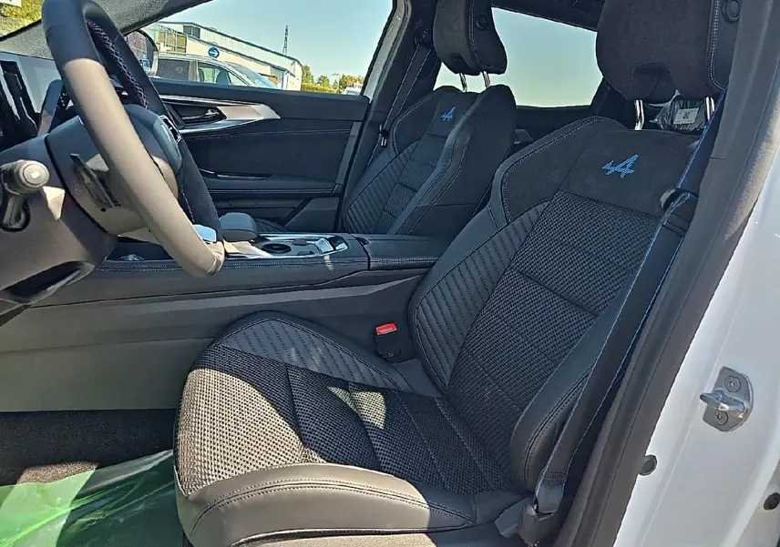 Vue intérieure côté conducteur du Renault Austral blanc nacré, sièges sport noirs avec logo Alpine bleu brodé.
