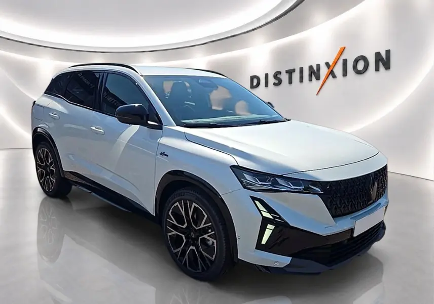 Renault Austral blanc nacré en 3/4 avant droit, avec jantes noires et phares LED distinctifs dans un showroom moderne.