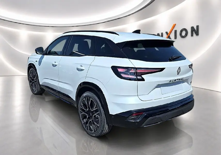 Vue 3/4 arrière droite du Renault Austral blanc nacré avec jantes noires et toit noir contrasté dans un showroom.