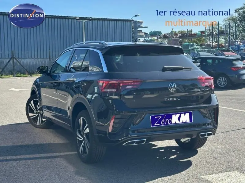 Volkswagen T-Roc noir intense nacré vu de 3/4 arrière droit, avec sorties d’échappement chromées et barres de toit.