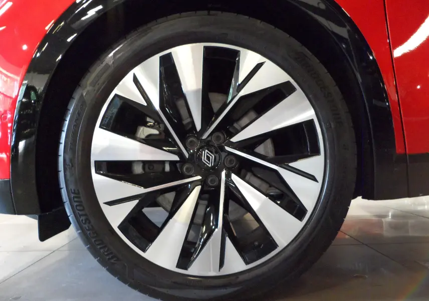 Gros plan sur la jante avant droite bicolore noire et argent du Renault Rafale E-Tech Rouge Flamme avec toit noir.