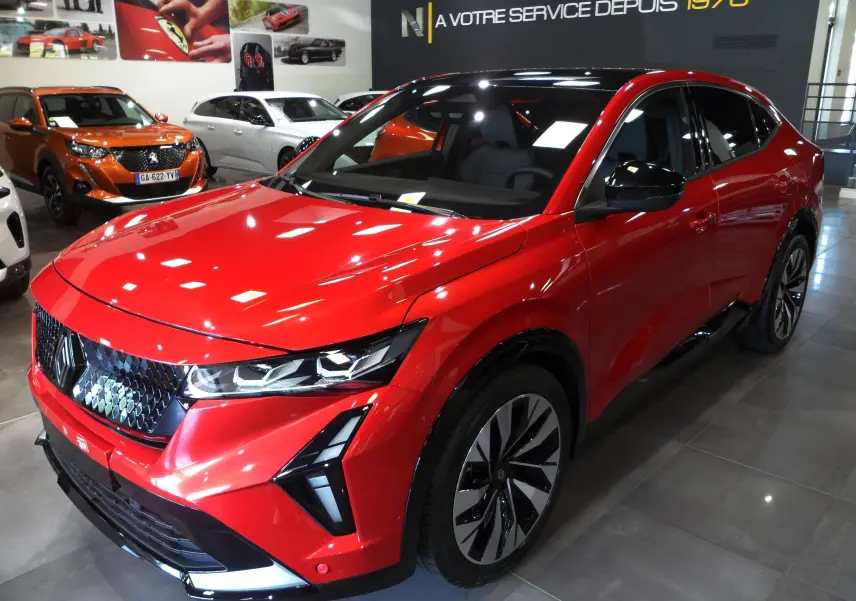 Renault Rafale E-Tech hybride rouge flamme avec toit noir, vue 3/4 avant droit en showroom lumineux.