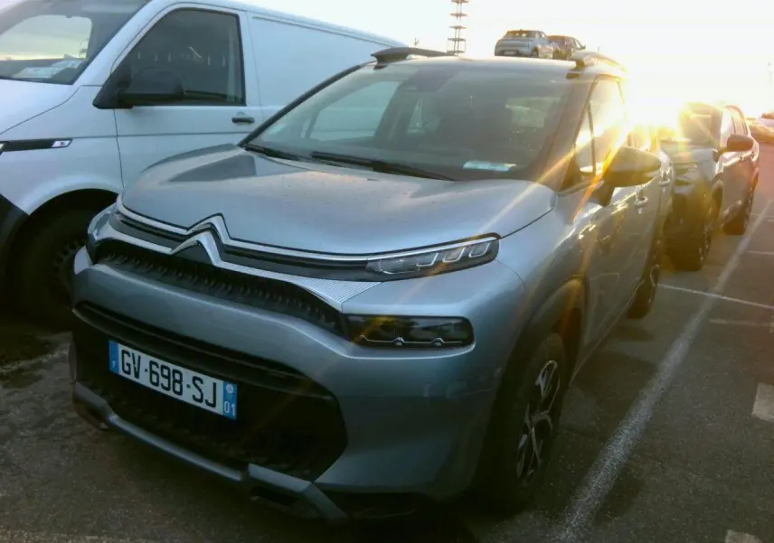 Citroën C3 Aircross gris foncé vue 3/4 avant droit avec jantes alliage et barres de toit noires.