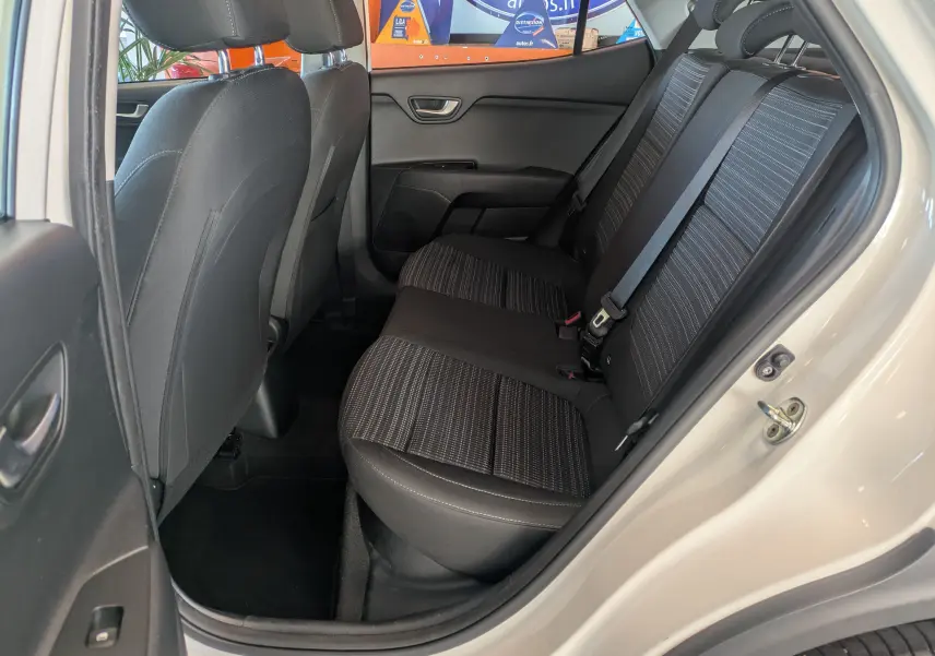 Vue intérieure côté droit sur les sièges arrière noirs à motifs du Kia Stonic blanc 2022, porte ouverte.