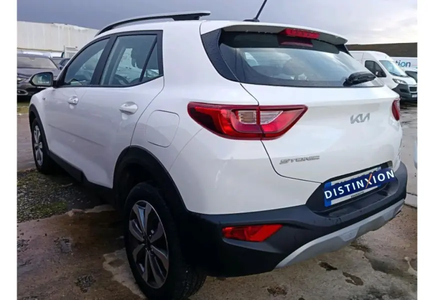 KIA Stonic blanc vue de profil côté gauche en intérieur, avec jantes alliage et toit noir contrasté.