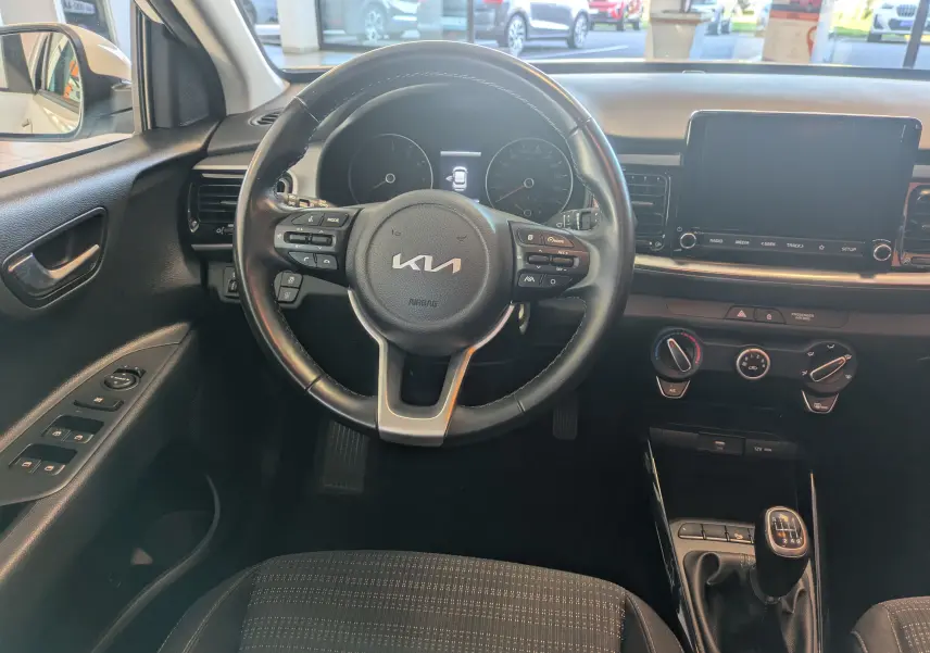 Vue intérieure centrée sur le volant noir et la console centrale du Kia Stonic 2022 avec boîte manuelle et écran tactile.