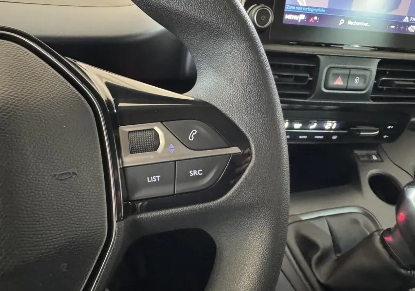 Gros plan sur la partie gauche du volant noir du Peugeot Rifter 2019 avec commandes audio et écran tactile de navigation visible.