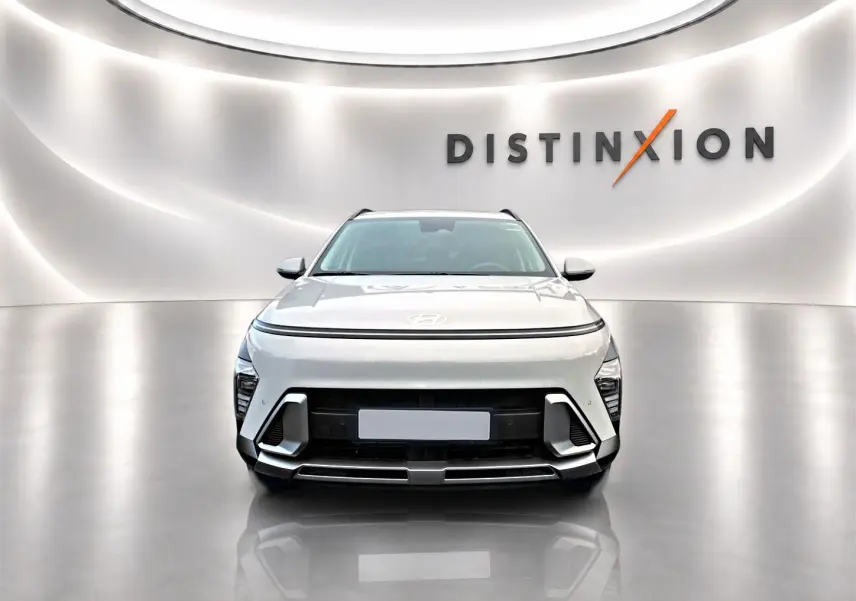 Vue avant d'un Hyundai Kona gris 2025 avec calandre noire et éclairage LED, sur fond blanc avec logo Distinxion.