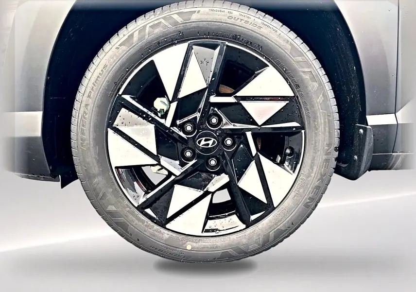 Gros plan sur la jante alliage noire et argentée du Hyundai Kona gris, mettant en valeur le logo Hyundai central.