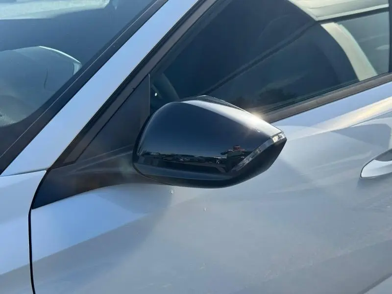 Rétroviseur extérieur droit noir brillant sur Peugeot 308 blanc Okénite, vue rapprochée côté conducteur.