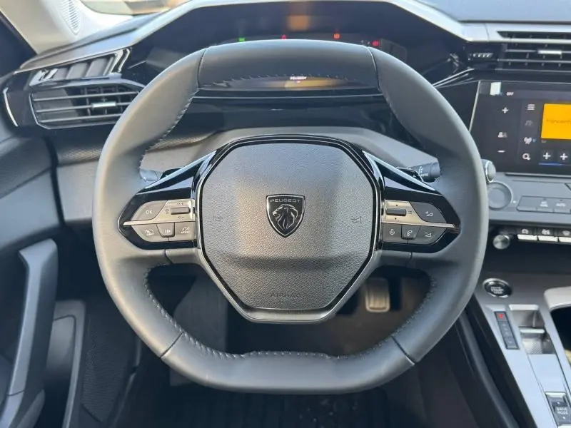 Vue frontale du volant multifonction noir de la Peugeot 308 1.5 BlueHDi 130ch avec tableau de bord et écran tactile.