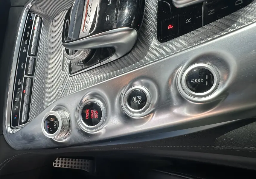 Gros plan sur la console centrale en aluminium brossé du Mercedes AMG GT 2015, avec levier de vitesse et boutons de contrôle.