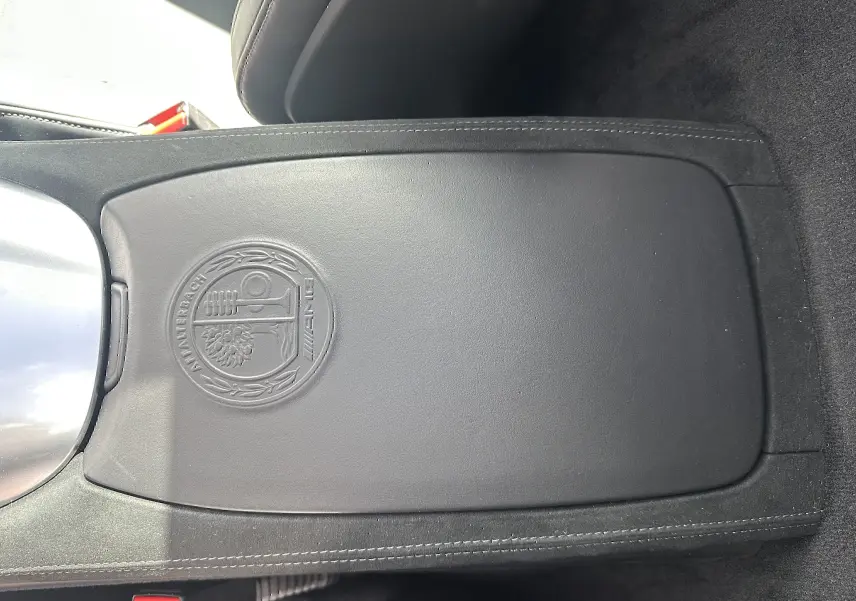 Détail intérieur montrant la console centrale en cuir noir avec logo AMG embossé sur Mercedes AMG GT gris foncé 2015.