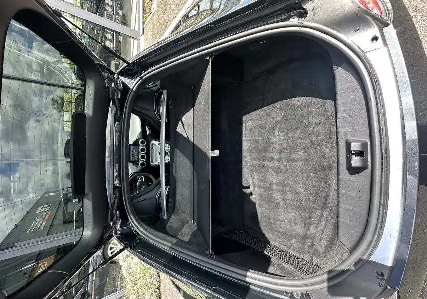 Vue plongeante sur le coffre avant ouvert d'une Mercedes AMG GT gris foncé, avec l'intérieur et le tableau de bord visibles.