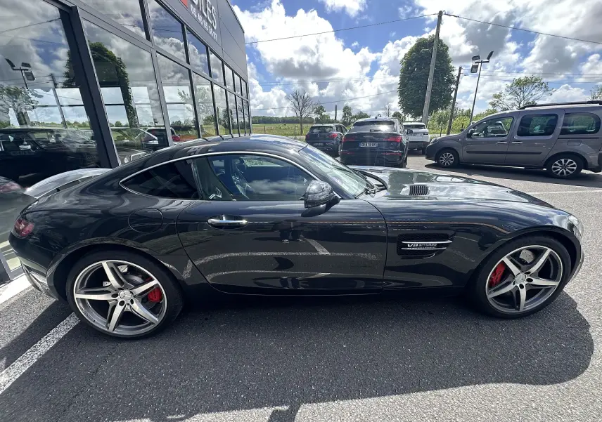 Vue de profil côté gauche d'une Mercedes AMG GT gris foncé avec étriers de frein rouges et jantes cinq branches.
