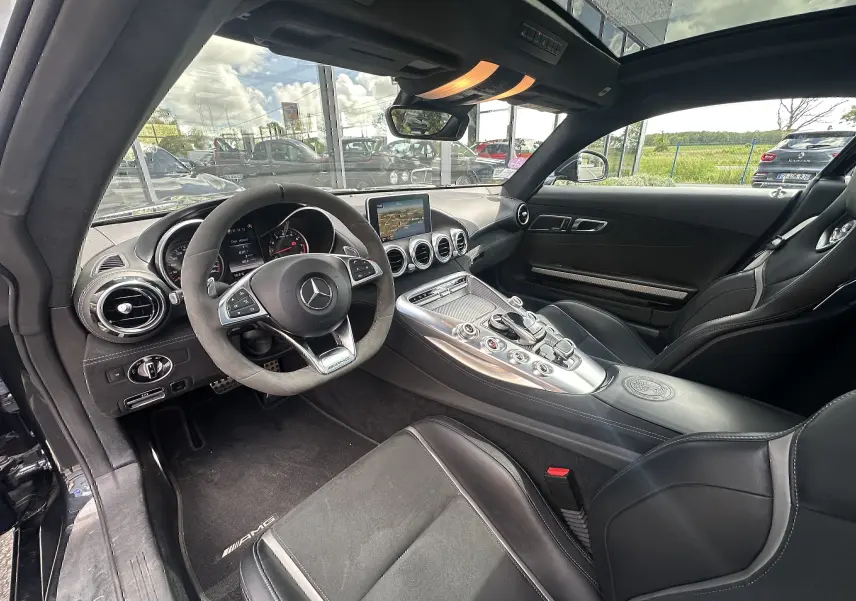 Intérieur noir du Mercedes AMG GT 2015 vu côté conducteur, avec volant sport et console centrale alu satinée.