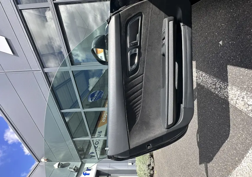 Vue en gros plan de la porte intérieure côté gauche du Mercedes AMG GT 2015 gris foncé avec garniture en alcantara et inserts carbone.