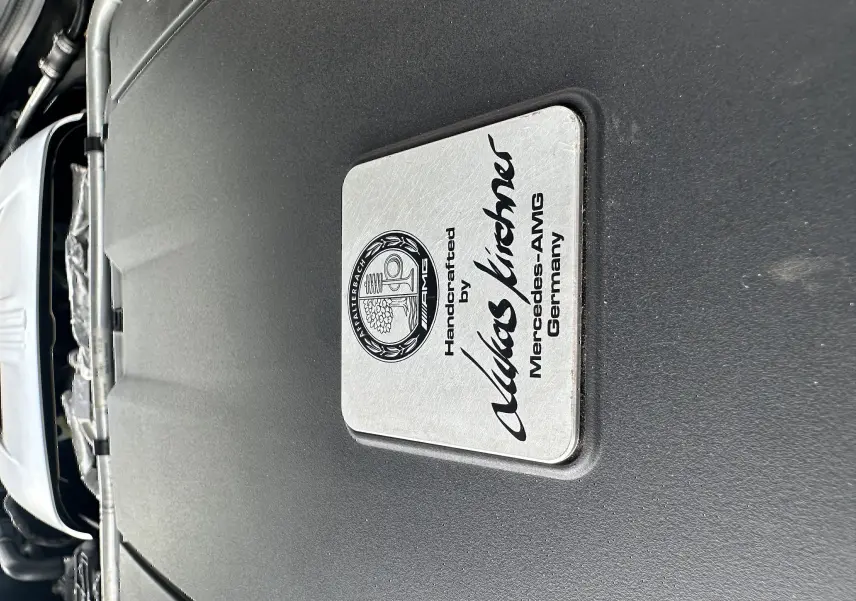 Gros plan sur la plaque du moteur gris foncé du Mercedes AMG GT 4.0 V8 510 S, signée du constructeur allemand.