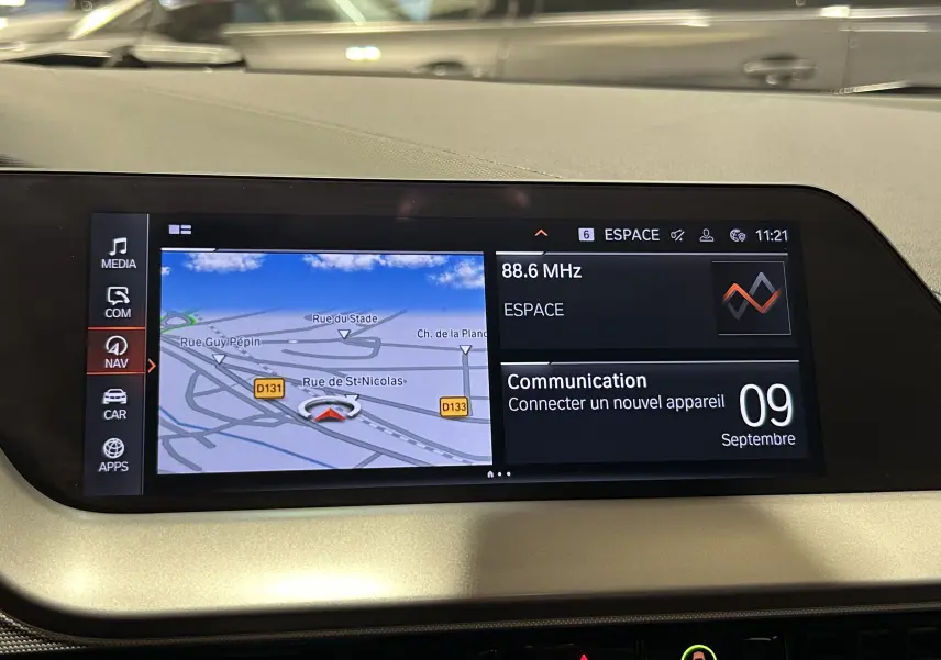 Écran central du tableau de bord de la BMW Série 1 noire 2023 affichant le GPS et les options multimédia.