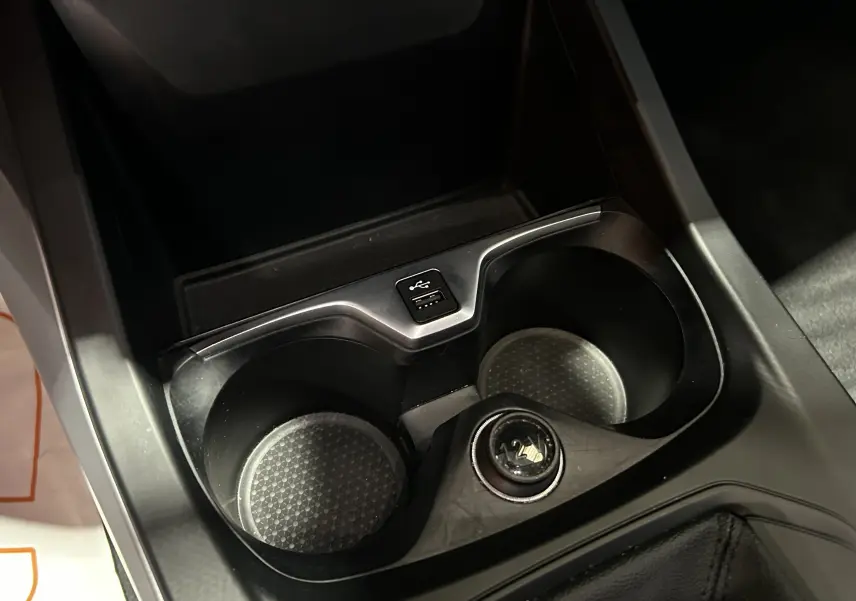 Gros plan sur les porte-gobelets et prise USB au centre de la console d'une BMW Série 1 noire 2023.