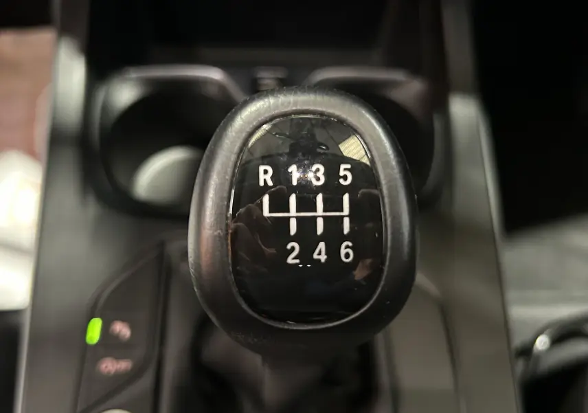 Le levier de vitesses manuel noir de la BMW Série 1 16d 2023, montrant les six rapports et la marche arrière.