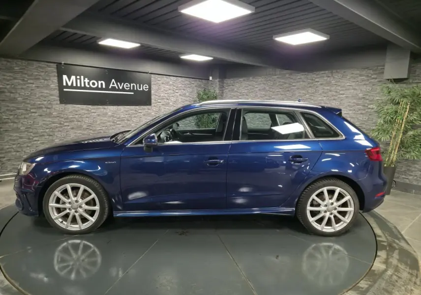 Audi A3 Sportback bleu vue de profil côté gauche dans un showroom avec jantes aluminium 10 branches.