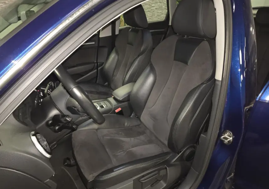 Intérieur avant droit d'une Audi A3 Sportback bleu, sièges sport en cuir et alcantara noirs, volant multifonction.