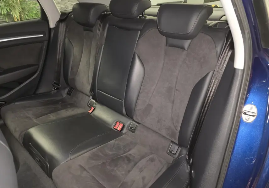 Vue intérieure sur la banquette arrière en alcantara et cuir noir d'une Audi A3 Sportback bleu 2015.
