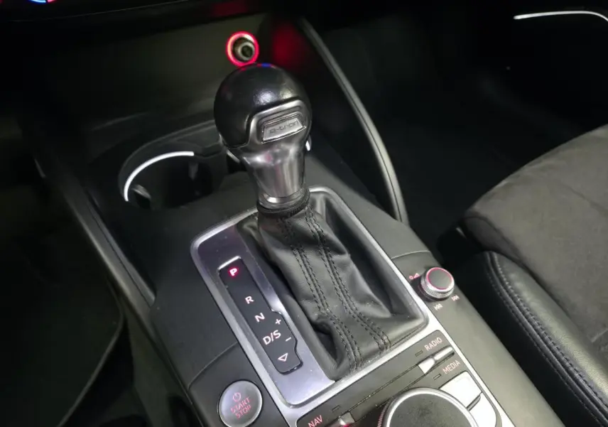 Gros plan sur la console centrale de l'Audi A3 Sportback hybride, levier de vitesse automatique e-tron et commandes MMI.