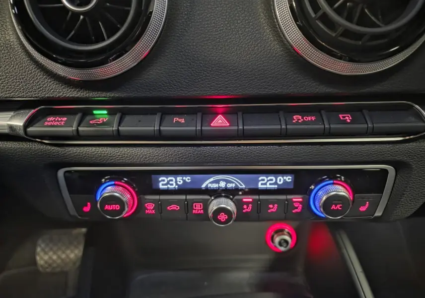 Tableau de bord intérieur de l'Audi A3 Sportback bleu, avec commandes climatisation et boutons éclairés rouges et bleus.