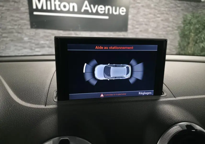 Écran MMI affichant l'aide au stationnement avec vue aérienne du break Audi A3 Sportback bleu en intérieur.