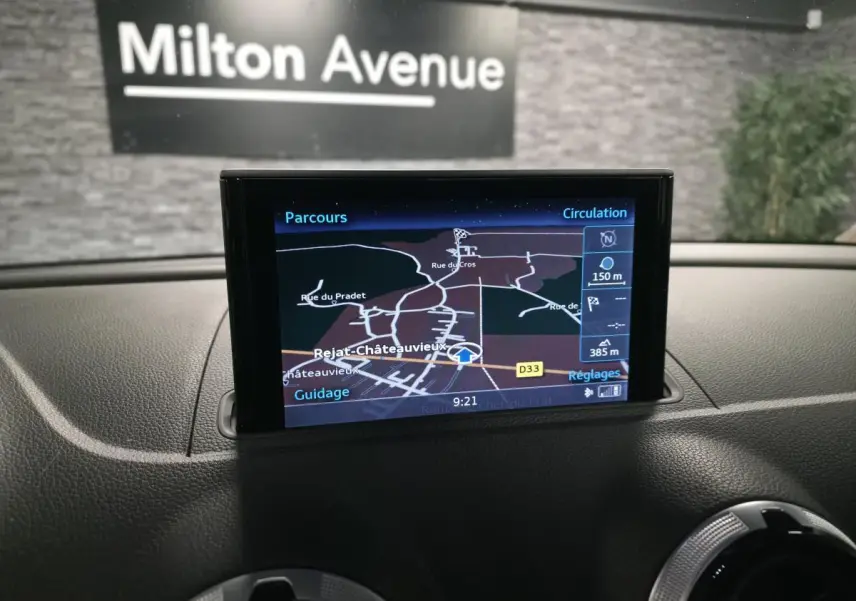 Écran MMI GPS Plus affichant la navigation dans l'habitacle d'une Audi A3 Sportback bleu, vue de face du tableau de bord.