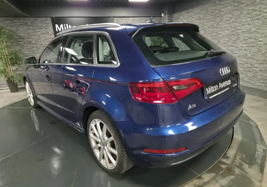 Audi A3 Sportback bleu en vue 3/4 arrière droit, avec jantes aluminium 10 branches et feux arrière LED.