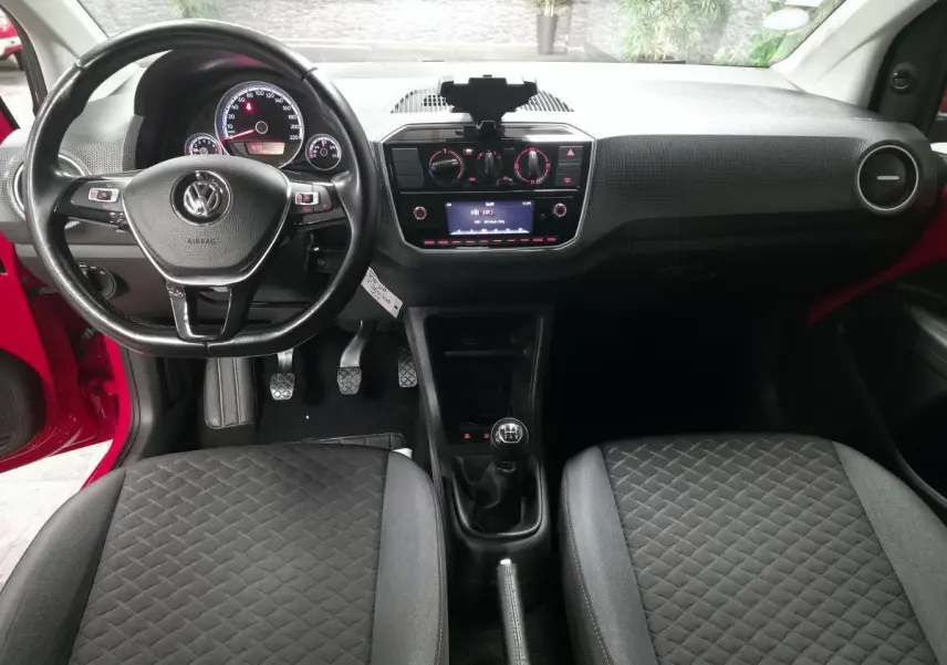 Intérieur de Volkswagen Up rouge 2018 vu de face, volant cuir multifonctions et levier de vitesses manuel au centre.