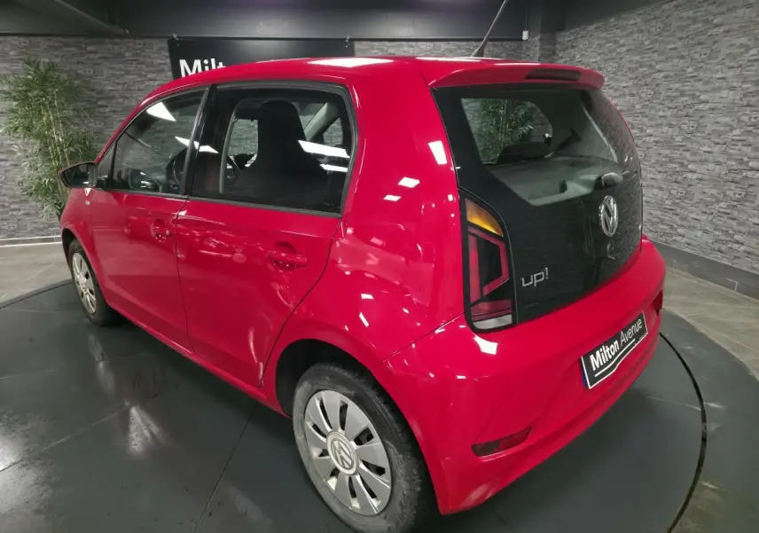 Volkswagen Up rouge vue 3/4 arrière droit, avec jantes acier et logo VW sur enjoliveurs spécifiques.