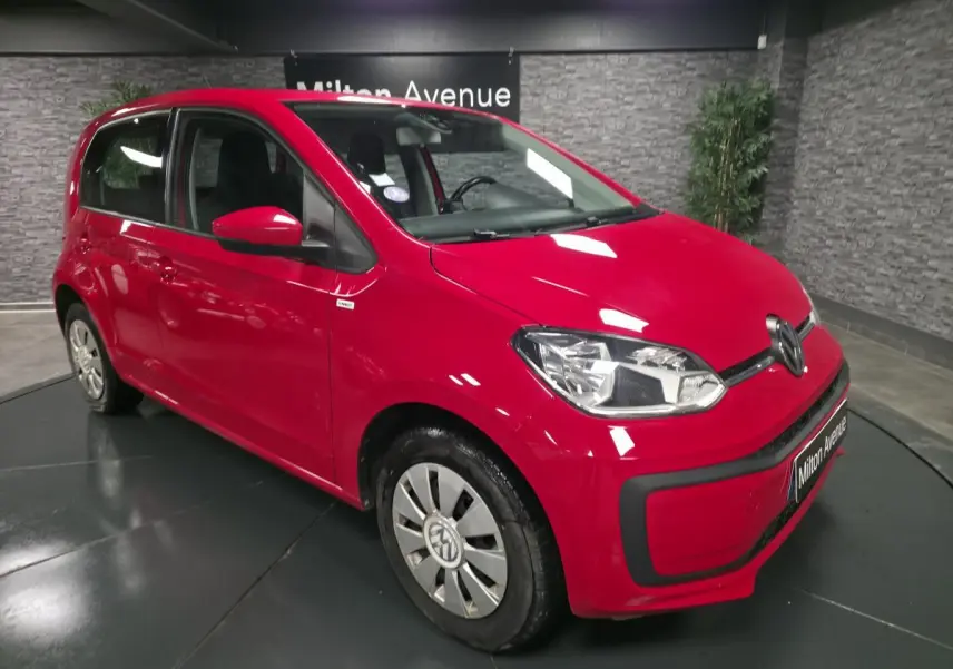 Vue 3/4 avant droit d'une Volkswagen Up rouge avec jantes acier et enjoliveurs spécifiques VW en aluminium.