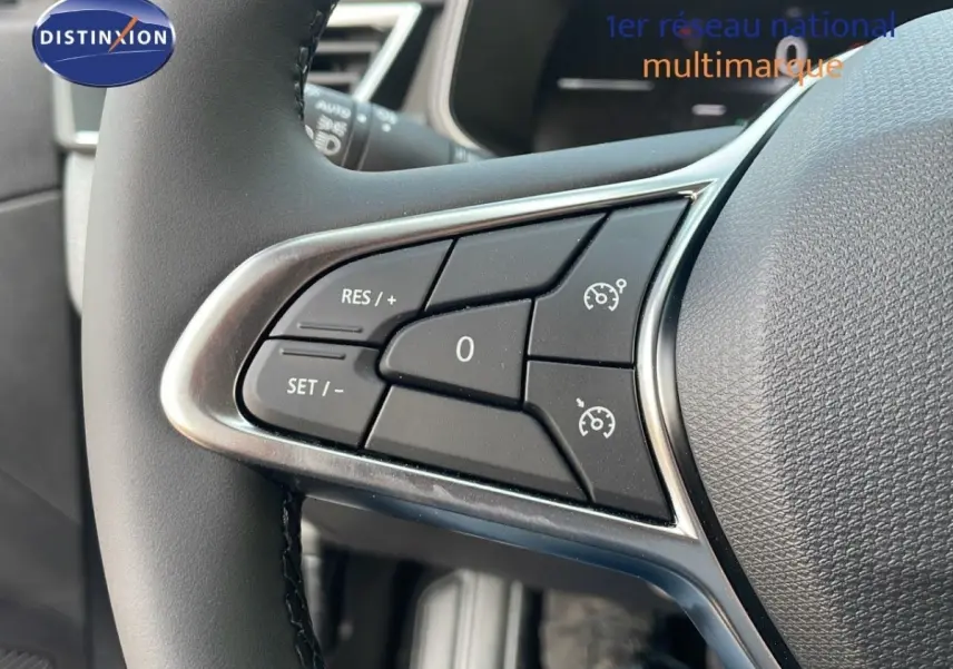 Gros plan sur les commandes du régulateur de vitesse au volant cuir d'une Renault Clio 2025, intérieur noir.