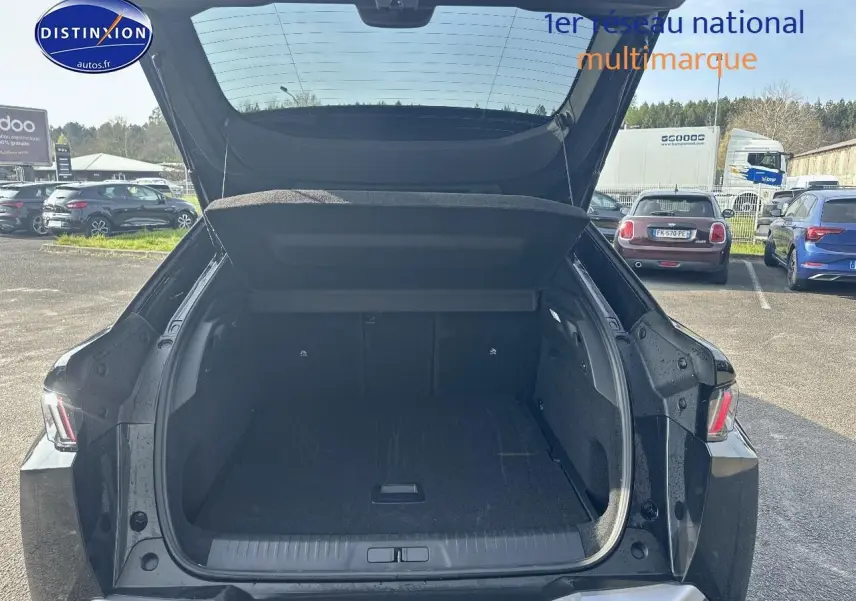 Coffre ouvert vue arrière d’un Peugeot 3008 noir perla nera meta 2024 sur parking extérieur.