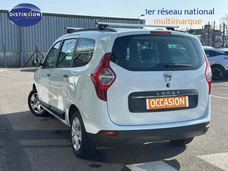 Vue 3/4 arrière droite d'un Dacia Lodgy blanc Glacier avec porte-vélos sur toit, en stationnement extérieur.