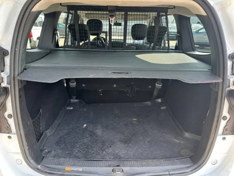 Coffre ouvert vu de l'arrière d'un Dacia Lodgy blanc Glacier 2022 avec cache-bagages et grille de séparation intérieure.