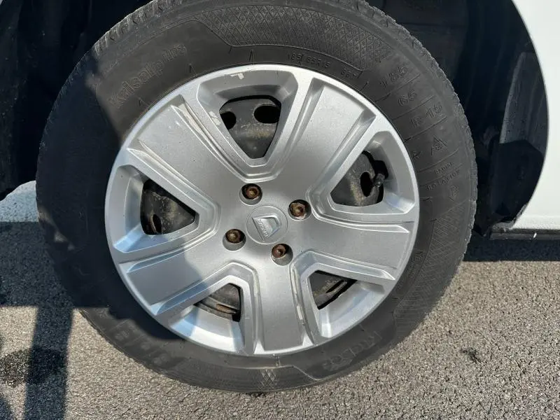 Gros plan sur la roue avant droite d’un Dacia Lodgy blanc Glacier, mettant en valeur la jante en alliage argentée.