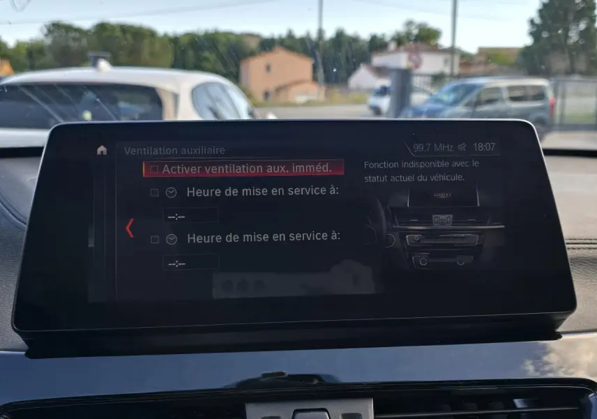 Vue intérieure du tableau de bord du BMW X1 noir, avec écran multimédia affichant les réglages de ventilation.