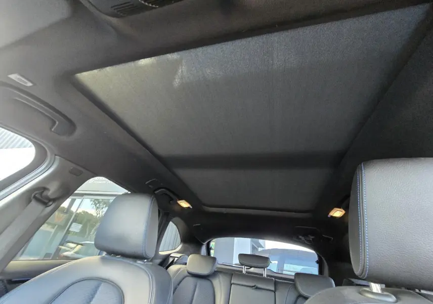 Vue intérieure du toit ouvrant panoramique et des sièges noirs avec surpiqûres bleues d'un BMW X1 F48 M Sport 2020.